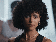a woman with curly hair is wearing hoop earrings