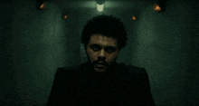 a man with a beard is standing in a dark hallway .
