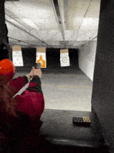 a woman is shooting a gun at a target with a green target