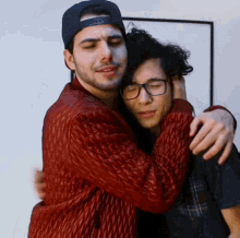 a man in a red jacket is hugging another man