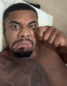 a shirtless man with a tattoo on his chest making a funny face