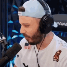 a man with a beard wearing headphones and a hat that says paw
