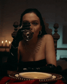 a woman wearing black gloves is holding a wine glass