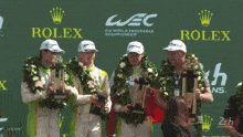 a group of men holding trophies in front of a rolex logo