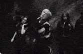 a group of people are dancing in front of a wall in a black and white photo