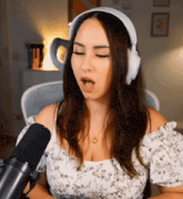 a woman wearing headphones is singing into a microphone with her mouth open