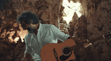 a man with glasses and a beard is holding a guitar