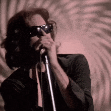 a man singing into a microphone with sunglasses on