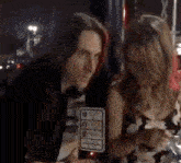 a man and a woman are sitting at a table with a wait sign above them