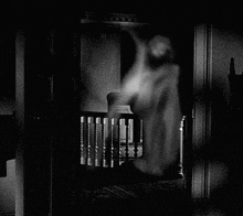 a black and white photo of a ghost standing in a dark room