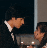 a man in a tuxedo and a woman in a white dress are looking into each other 's eyes