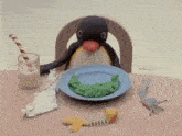 a penguin is sitting at a table with a plate of food and a glass of milk .