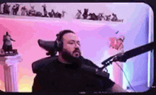 a man with a beard is sitting in front of a microphone in a video game room .