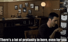 a man sitting at a desk with the words " there 's a lot of profanity in here even for you " behind him