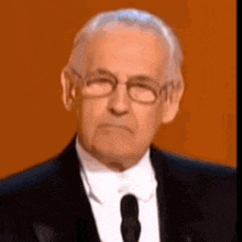 a man wearing glasses and a suit and tie looks at the camera