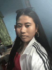 a woman wearing a white jacket with black stripes and hoop earrings