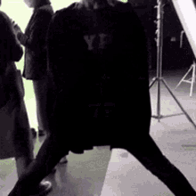 a man in a black shirt with the word yf on it is standing on one leg .