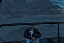 a man sitting on a balcony overlooking mountains