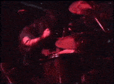 a man is playing drums on a stage in a dark room