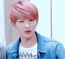 a young man with pink hair is wearing a denim jacket and a white shirt