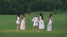 a group of women standing in a field holding colored powder in their hands