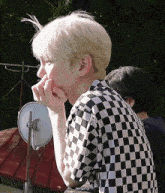 a man wearing a black and white checkered shirt holds his nose