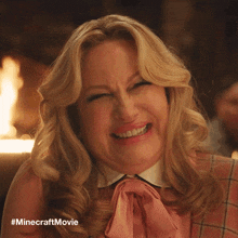 a woman in a pink shirt is making a funny face with #minecraftmovie written on the bottom
