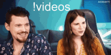 a man and a woman are smiling in front of a blue background that says ! videos