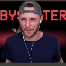 a man wearing a hat and headphones is making a funny face in front of a screen that says byster .