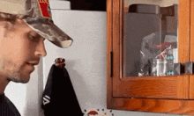 a man wearing a camo hat is standing in front of a refrigerator