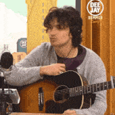 a man wearing headphones playing a guitar in front of a sign that says dee jay summer camp