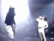 two women are singing into microphones on stage in front of a crowd .
