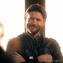 a man in a black leather jacket is smiling and says hi