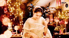 a woman in a white dress is standing in front of a table with candles and a sign that says sona
