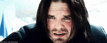a close up of a man with long black hair and a beard .