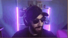 a man with a beard is wearing headphones and sunglasses in a room with purple lights .