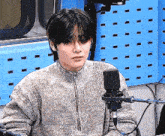 a man is sitting in front of a microphone in a room .