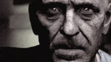 a close up of a man 's face with a beard and a serious look on his face .