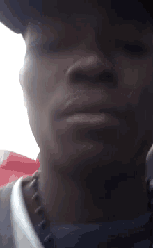 a close up of a man 's face wearing a hat and a necklace