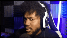 a man with a beard wearing headphones is making a funny face .
