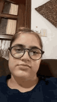 a woman wearing glasses is sitting on a couch .