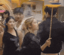 a group of people are standing around a man holding a stick while a woman looks on .