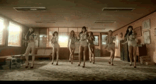 a group of women are dancing in a room with a couch