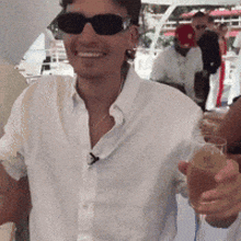 a man wearing sunglasses is smiling and holding a glass of wine