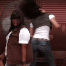 a woman in a brown vest is standing next to a woman in a white shirt