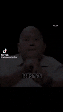 a bald man in a white shirt is making a gesture with his hands and says pekan .