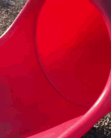 a shirtless man sits on a red slide wearing a black hat