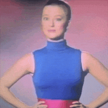 a woman with her hands on her hips is wearing a blue top and a red skirt .