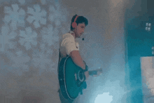 a man wearing headphones and a headset is playing a guitar .