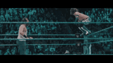 two wrestlers are fighting in a ring with a crowd in the background .
